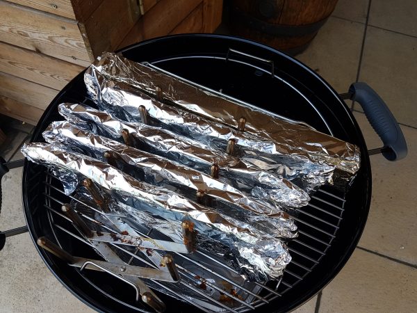 Na 3 uur haal je de spareribs eruit. Leg elke spareribs op een flink stuk aluminiumfolie. Spuit of smeer de spareribs in met het eerder gemaakt mengsel van appelsap, whisky en appelciderazijn.
Pak de sparerib goed in. Zorg ervoor dat er geen stukjes bot door de aluminiumfolie prikt, desnoods nog een laag aluminiumfolie gebruiken.