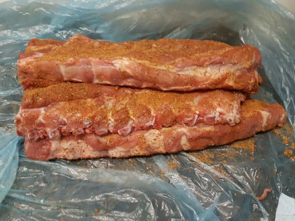 Bestrooi de bevleesde kant van de spareribs rijkelijk met een rub naar keuze. Wrijf de rub er goed in. Stapel de spareribs goed strak in plastic in zet weg in de koelkast. Liefst doe je dit de avond vantevoren